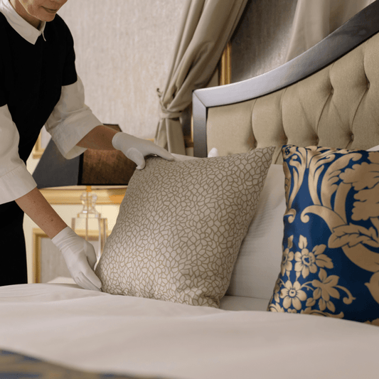 Hands fluffing pillows to achieve a pristine bed look